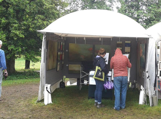 Customers perusing artwork inside a white tent at Arts in the Park festival, Byrd Park in Richmond, VA