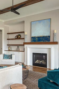 Indigo blue abstract seascape painting "Broken Rules," digital download by Victoria Primicias, decorates the fireplace.