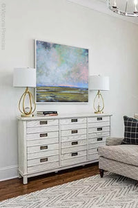 Large sky abstract coastal wall art "Delicate Dance," digital download by Victoria Primicias, decorates the living room.