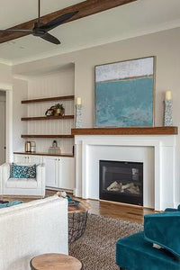 Teal abstract ocean painting "Merchant Crossing," printable wall art by Victoria Primicias, decorates the fireplace.